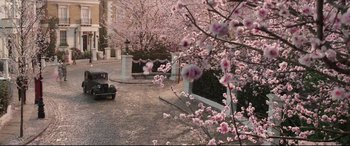 Movie still from “Mary Poppins Returns” (2018), directed by Rob Marshall – A car parked on the side of the road next to some trees; Extreme Wide shot, High angle