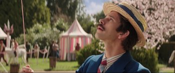 Movie still from “Mary Poppins Returns” (2018), directed by Rob Marshall – A man in a straw hat and a tie looks up into the sky; Close Up shot, Low angle