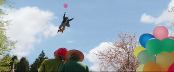 Movie still from “Mary Poppins Returns” (2018), directed by Rob Marshall – A man flying through the air while holding onto a pink balloon; Wide shot, Low angle