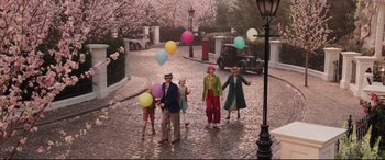 Movie still from “Mary Poppins Returns” (2018), directed by Rob Marshall – A group of people walking down a street with balloons; Wide shot, High angle