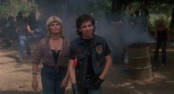 Movie still from “Mask” (1985), directed by Peter Bogdanovich – A man and a woman are walking in the woods; Medium shot, Low angle