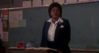 Movie still from “Mask” (1985), directed by Peter Bogdanovich – A woman standing in front of a chalkboard in a classroom; Medium shot, Low angle