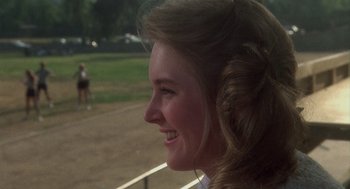 Movie still from “Mask” (1985), directed by Peter Bogdanovich – A person with long brown hair smiling; Close Up shot, Over the shoulder angle