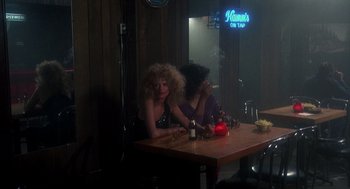 Movie still from “Mask” (1985), directed by Peter Bogdanovich – Two women sitting at a table in front of a neon sign; Wide shot, Over the shoulder angle