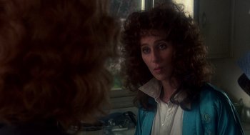 Movie still from “Mask” (1985), directed by Peter Bogdanovich – A young woman with long curly hair looking into a mirror; Close Up shot, Over the shoulder angle