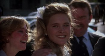 Movie still from “Mask” (1985), directed by Peter Bogdanovich – A woman with a flower in her hair smiling for the camera; Close Up shot, Over the shoulder angle