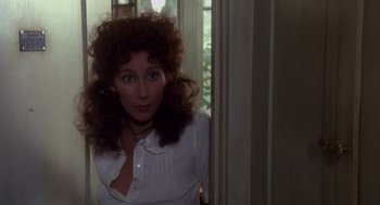 Movie still from “Mask” (1985), directed by Peter Bogdanovich – A woman in a white shirt is leaning against a wall; Close Up shot, Over the shoulder angle