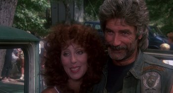 Movie still from “Mask” (1985), directed by Peter Bogdanovich – A man and a woman pose for a picture; Close Up shot, Over the shoulder angle