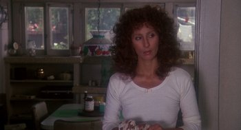 Movie still from “Mask” (1985), directed by Peter Bogdanovich – A woman sitting at a table holding a piece of food; Close Up shot, Over the shoulder angle