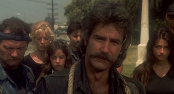 Movie still from “Mask” (1985), directed by Peter Bogdanovich – A group of people standing next to each other on a street; Close Up shot, Over the shoulder angle