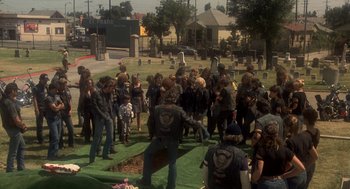 Movie still from “Mask” (1985), directed by Peter Bogdanovich – A group of people standing around a grave; Wide shot, High angle