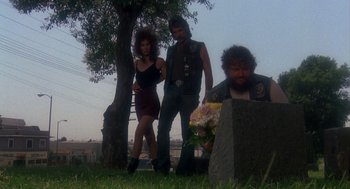 Movie still from “Mask” (1985), directed by Peter Bogdanovich – A man and a woman standing in front of a grave; Wide shot, Low angle