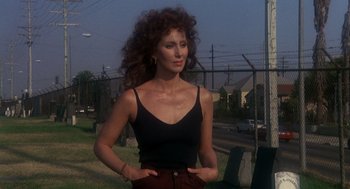 Movie still from “Mask” (1985), directed by Peter Bogdanovich – A woman standing in the grass with her hands on her hips; Medium shot, Low angle