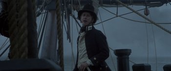 Movie still from “Master and Commander: The Far Side of the World” (2003), directed by Peter Weir – A man in a top hat and jacket on a boat; Medium shot, Low angle