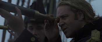 Movie still from “Master and Commander: The Far Side of the World” (2003), directed by Peter Weir – A man holding a baseball bat up to his eye; Close Up shot, Over the shoulder angle