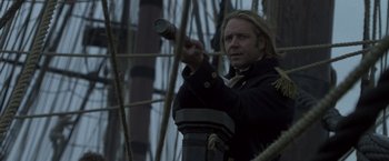 Movie still from “Master and Commander: The Far Side of the World” (2003), directed by Peter Weir – A man in a black jacket holding a telescope; Close Up shot, Over the shoulder angle