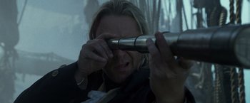 Movie still from “Master and Commander: The Far Side of the World” (2003), directed by Peter Weir – A man looking through a telescope at something in front of him; Close Up shot, Over the shoulder angle