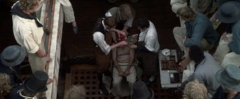 Movie still from “Master and Commander: The Far Side of the World” (2003), directed by Peter Weir – A group of people standing next to each other on the ground; Medium shot, Overhead angle