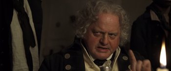 Movie still from “Master and Commander: The Far Side of the World” (2003), directed by Peter Weir – An old man with a white beard and a black jacket; Close Up shot, Over the shoulder angle