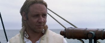 Movie still from “Master and Commander: The Far Side of the World” (2003), directed by Peter Weir – A person on a boat wearing a vest; Close Up shot, Over the shoulder angle