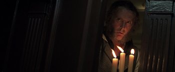 Movie still from “Master and Commander: The Far Side of the World” (2003), directed by Peter Weir – A man with a long beard is holding a lit candle; Close Up shot, Over the shoulder angle