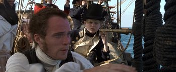 Movie still from “Master and Commander: The Far Side of the World” (2003), directed by Peter Weir – A group of people on a boat in the water; Close Up shot, Over the shoulder angle