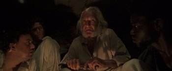 Movie still from “Master and Commander: The Far Side of the World” (2003), directed by Peter Weir – An old man with white hair and a white beard is holding a knife; Close Up shot, Low angle