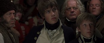 Movie still from “Master and Commander: The Far Side of the World” (2003), directed by Peter Weir – A young man wearing a black jacket and a white shirt; Close Up shot, Over the shoulder angle