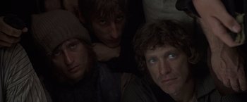 Movie still from “Master and Commander: The Far Side of the World” (2003), directed by Peter Weir – A group of people that are sitting in the dark; Close Up shot, High angle