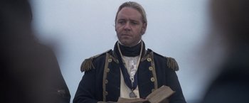 Movie still from “Master and Commander: The Far Side of the World” (2003), directed by Peter Weir – A person holding a book wearing a uniform; Close Up shot, Low angle