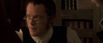 Movie still from “Master and Commander: The Far Side of the World” (2003), directed by Peter Weir – A person wearing glasses and a vest; Close Up shot, Over the shoulder angle