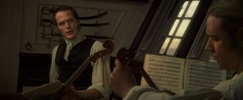 Movie still from “Master and Commander: The Far Side of the World” (2003), directed by Peter Weir – A woman holding a violin in front of a man playing the violin; Close Up shot, Over the shoulder angle