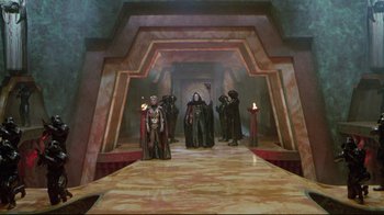 Movie still from “Masters of the Universe” (1987), directed by Gary Goddard – A group of people standing in front of a stage; Extreme Wide shot, High angle