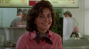 Movie still from “Masters of the Universe” (1987), directed by Gary Goddard – A woman in a red and white checkered shirt and a brown bow tie; Close Up shot, Over the shoulder angle