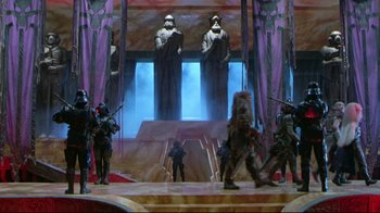 Movie still from “Masters of the Universe” (1987), directed by Gary Goddard – A group of people standing on top of a stage; Extreme Wide shot, Low angle
