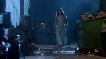 Movie still from “Masters of the Universe” (1987), directed by Gary Goddard – A woman standing in a dark room next to trash cans; Wide shot, Low angle