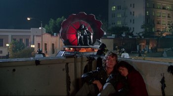 Movie still from “Masters of the Universe” (1987), directed by Gary Goddard – Two people sitting on top of a building; Wide shot, Low angle