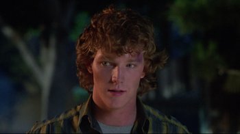 Movie still from “Masters of the Universe” (1987), directed by Gary Goddard – A young man with curly brown hair wearing a yellow and black striped shirt; Close Up shot, Over the shoulder angle