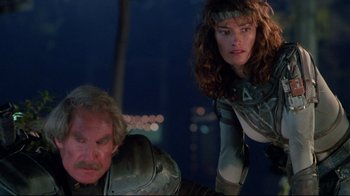 Movie still from “Masters of the Universe” (1987), directed by Gary Goddard – A man and a woman standing next to each other in front of a building; Medium shot, Low angle