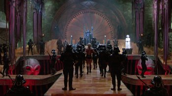 Movie still from “Masters of the Universe” (1987), directed by Gary Goddard – A group of people standing on top of a wooden floor; Extreme Wide shot, High angle