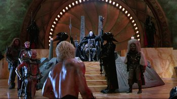 Movie still from “Masters of the Universe” (1987), directed by Gary Goddard – A group of people standing in front of a statue; Wide shot, Low angle