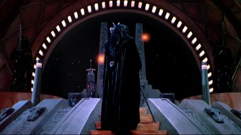 Movie still from “Masters of the Universe” (1987), directed by Gary Goddard – A man in a black robe stands on steps in front of a building; Wide shot, Low angle