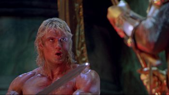Movie still from “Masters of the Universe” (1987), directed by Gary Goddard – A man that is holding a sword in his hand; Close Up shot, Low angle