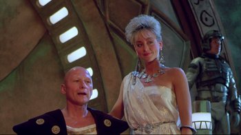 Movie still from “Masters of the Universe” (1987), directed by Gary Goddard – A man standing next to a woman in a white dress; Medium shot, Low angle