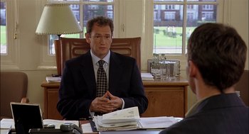 Movie still from “Match Point” (2005), directed by Woody Allen – A man sitting at a desk in front of another man in a suit; Medium shot, Over the shoulder angle