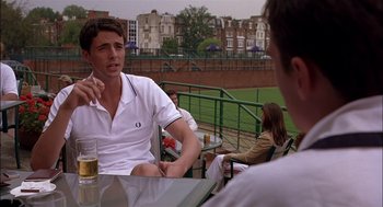 Movie still from “Match Point” (2005), directed by Woody Allen – A man sitting at a table talking on a cell phone; Medium shot, Over the shoulder angle