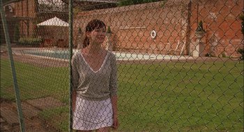 Movie still from “Match Point” (2005), directed by Woody Allen – A woman standing in front of a chain link fence; Wide shot, Over the shoulder angle