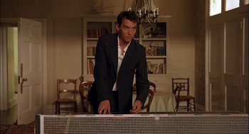 Movie still from “Match Point” (2005), directed by Woody Allen – A man in a black suit standing at a piano; Medium shot, Low angle