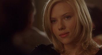 Movie still from “Match Point” (2005), directed by Woody Allen – A beautiful young blond woman looking at the camera while sitting down; Close Up shot, Over the shoulder angle