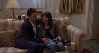 Movie still from “Match Point” (2005), directed by Woody Allen – A man and a woman sitting on a couch looking at a book; Medium shot, Low angle